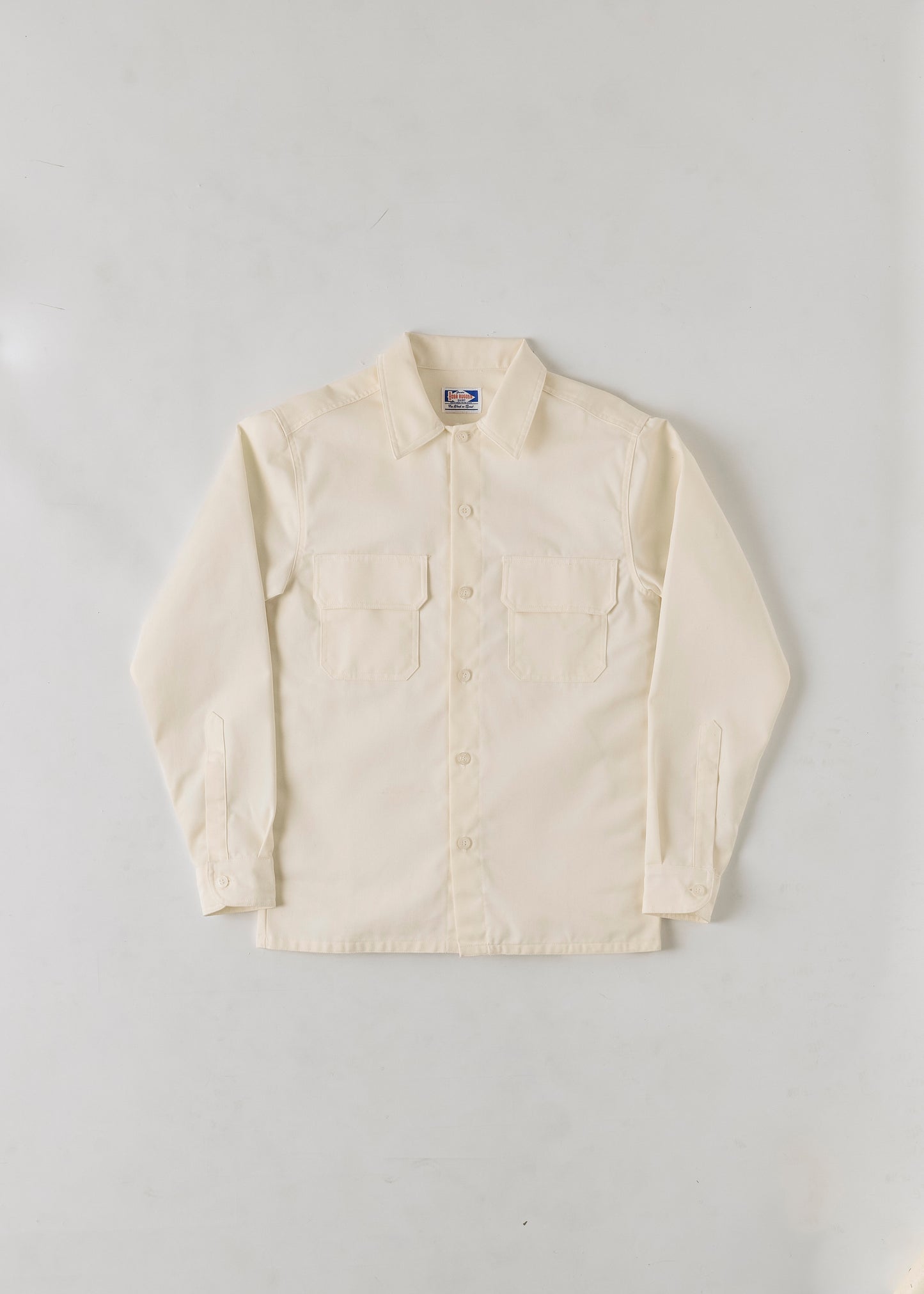 Flat lay of a cream coloured button up collared long sleeve shirt on a grey background.