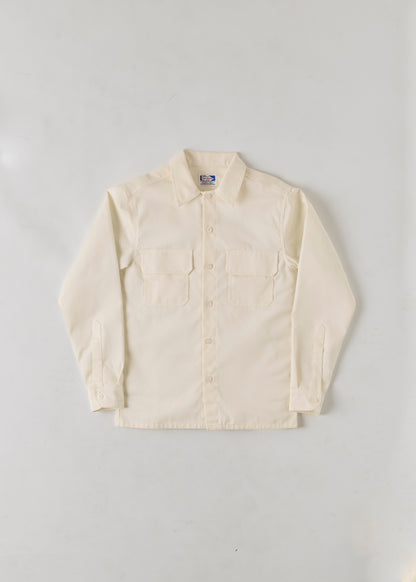 Flat lay of a cream coloured button up collared long sleeve shirt on a grey background.