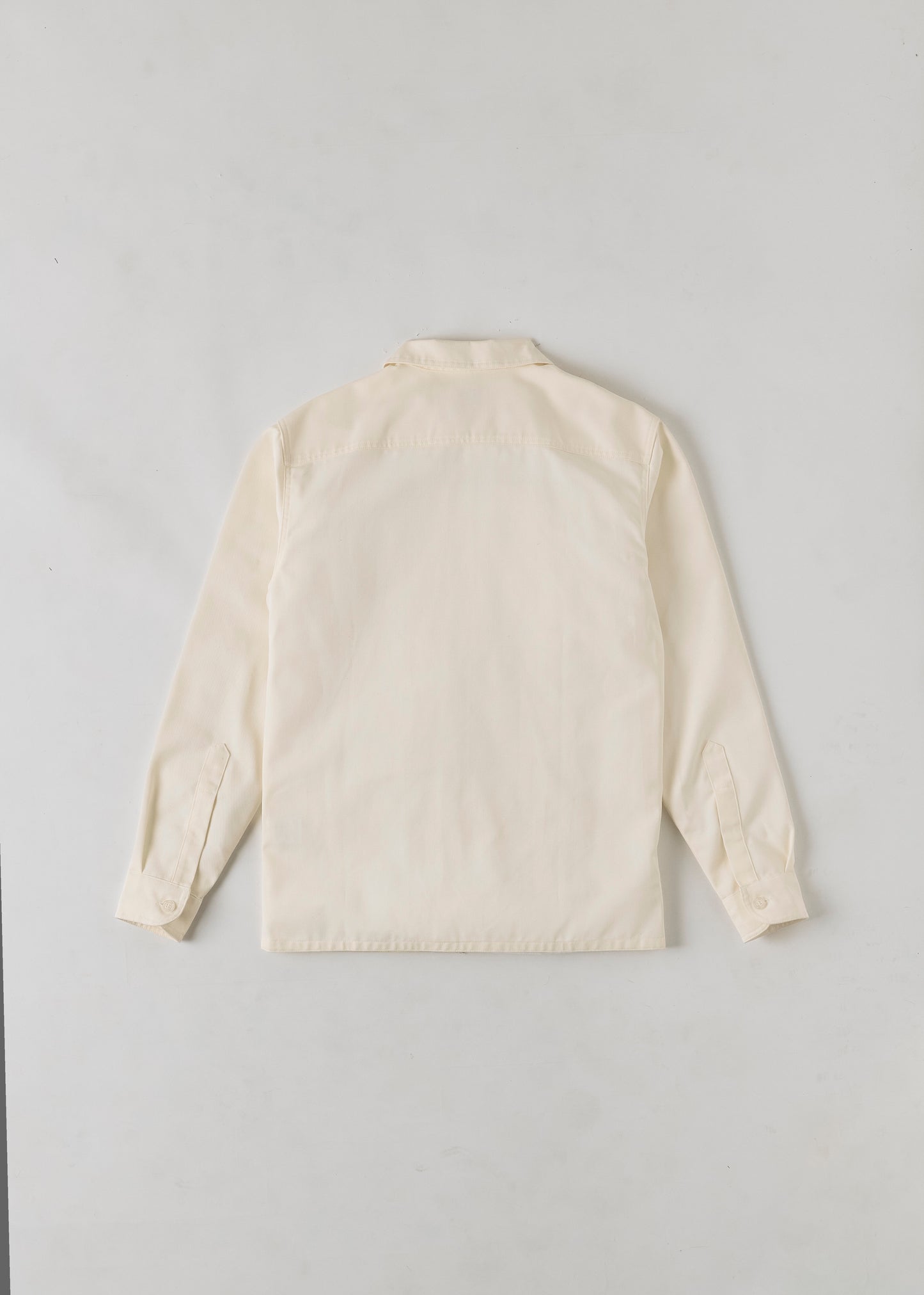 Rear view of a cream coloured button up long sleeve shirt. 