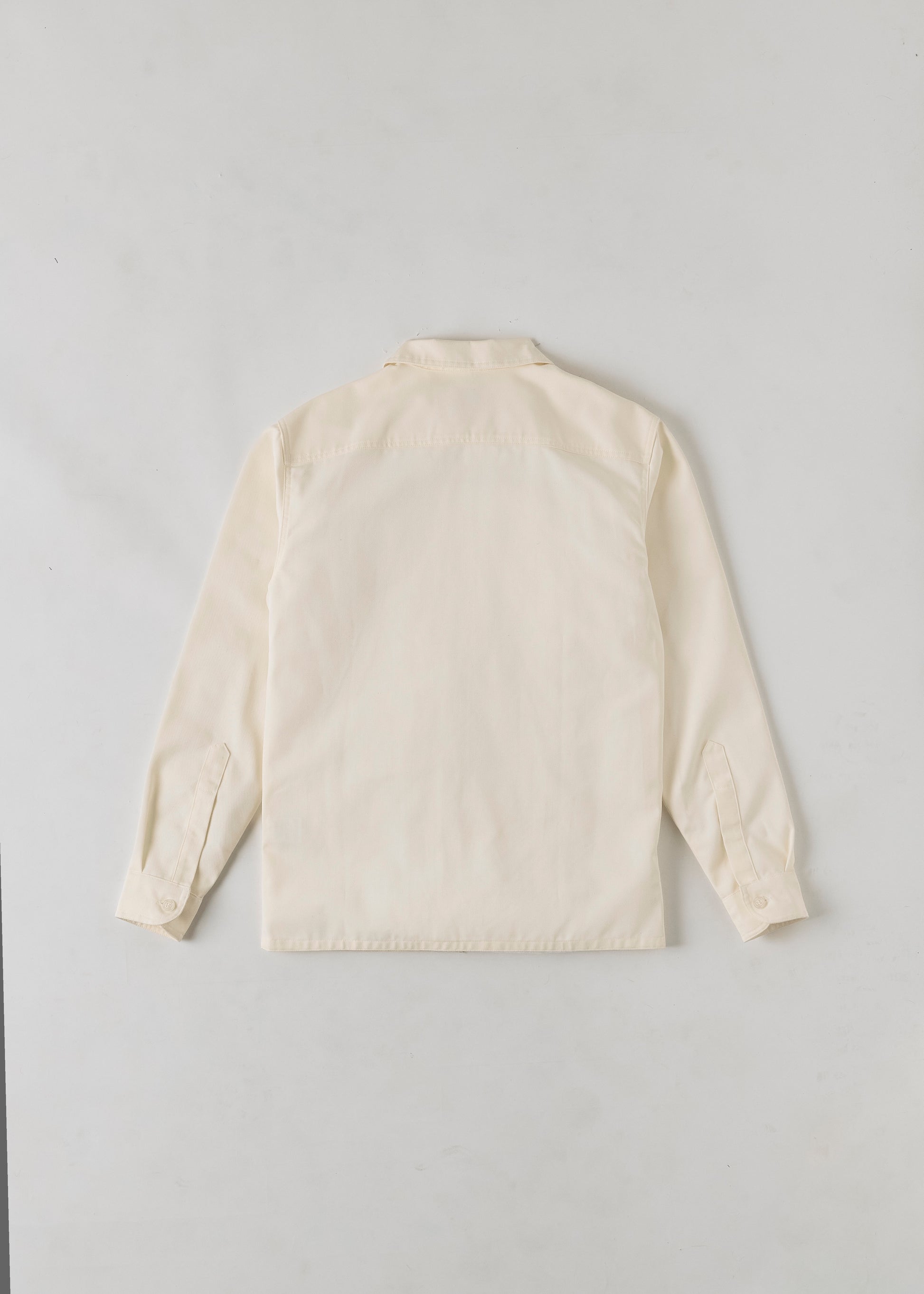 Rear view of a cream coloured button up long sleeve shirt. 