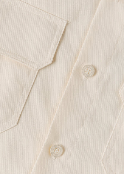 Close up of a cream coloured button on a cream coloured shirt.